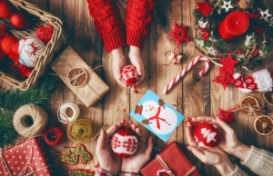 A cozy holiday crafting scene with hands decorating ornaments, wrapped gifts, ribbons, and a cheerful snowman card on a wooden table, perfect inspiration for heartfelt christmas card messages.