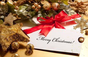 A Christmas greeting card displayed among gold stars, baubles, and holly décor, inspiring meaningful christmas card messages.